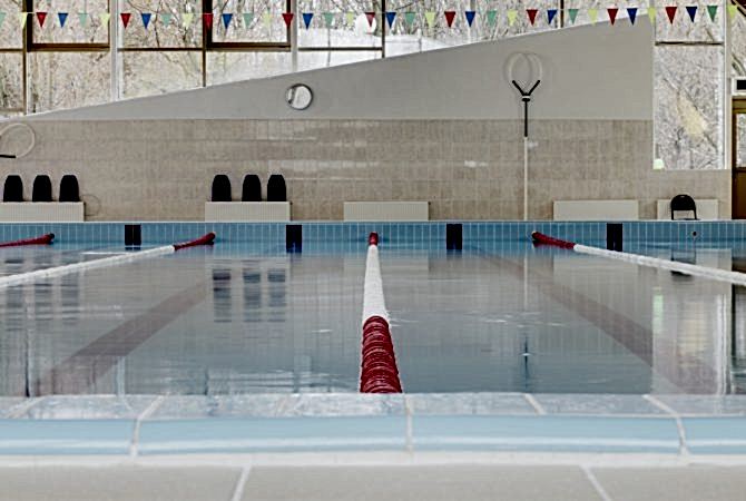 Indoor swimming pool, red and white dividers in swim lanes, surface view.